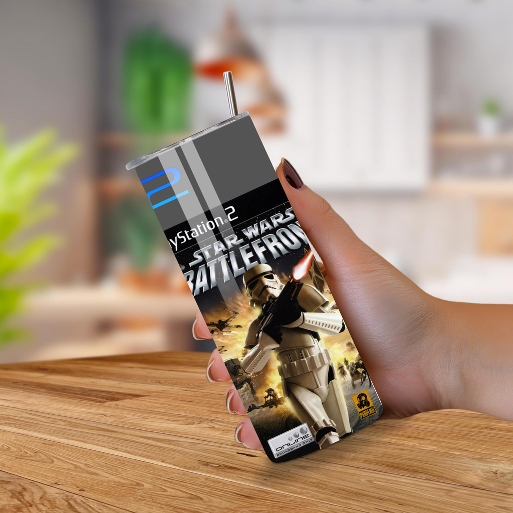 Hand holding a PlayStation 2 Star Wars Battlefront tumbler on a wooden surface.