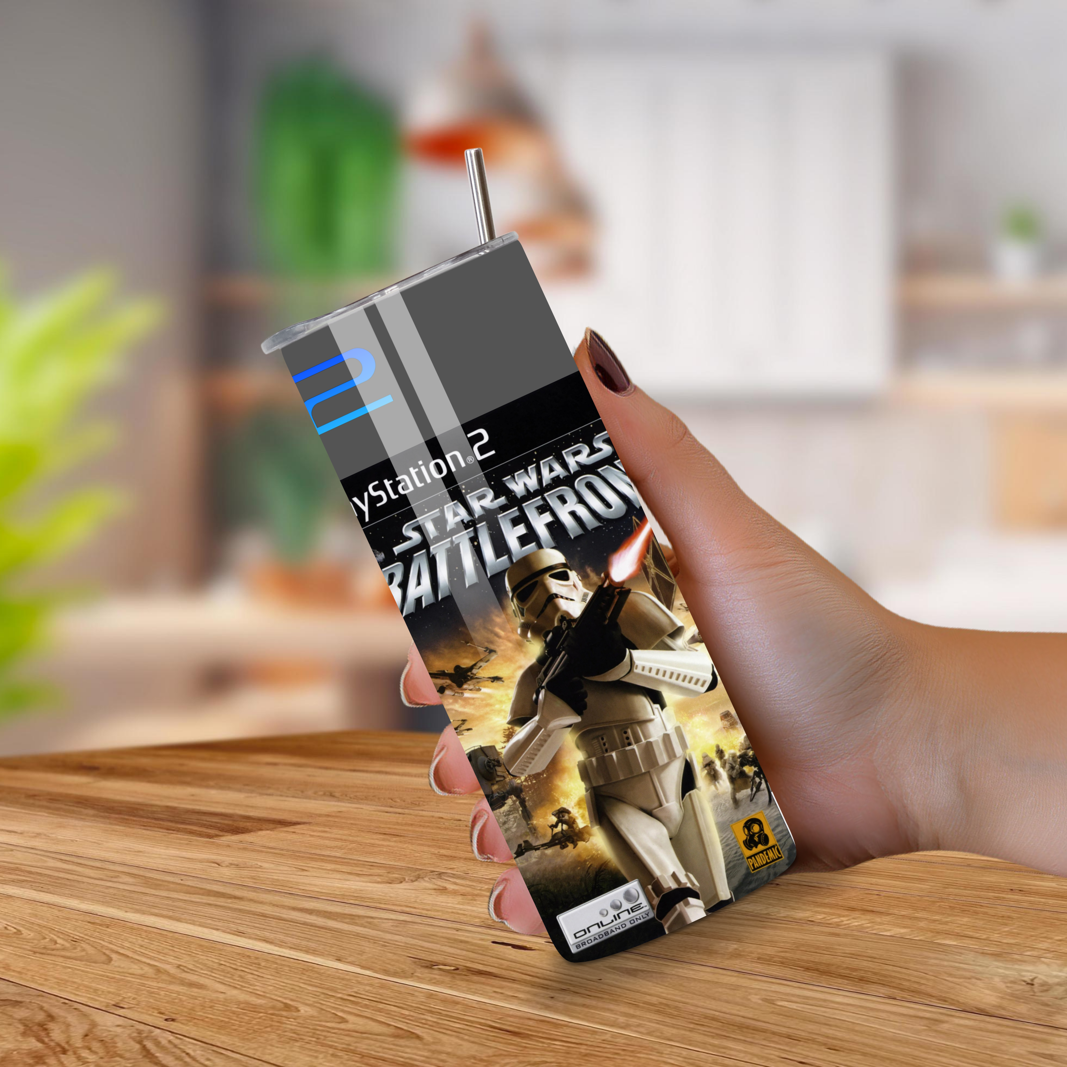 Hand holding a PlayStation 2 Star Wars Battlefront tumbler on a wooden surface.
