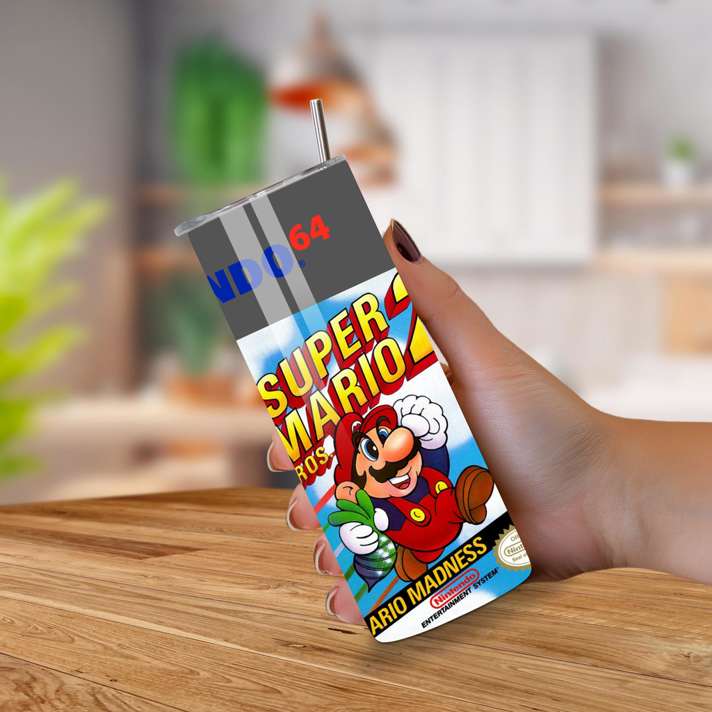 Super Mario-themed tumbler with a straw held by a hand on a wooden surface.