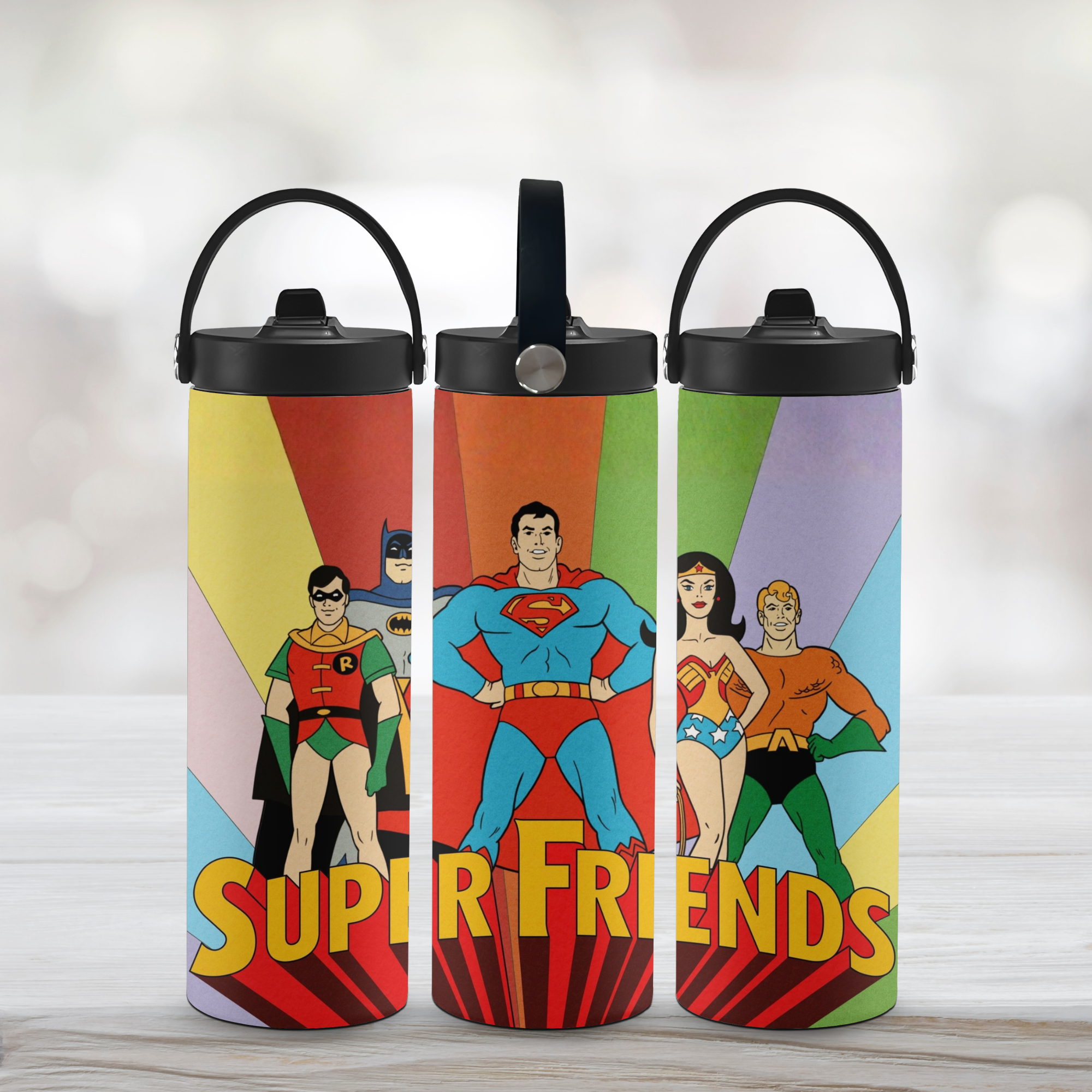 Three water bottle tumblers with Super Friends design on a light background