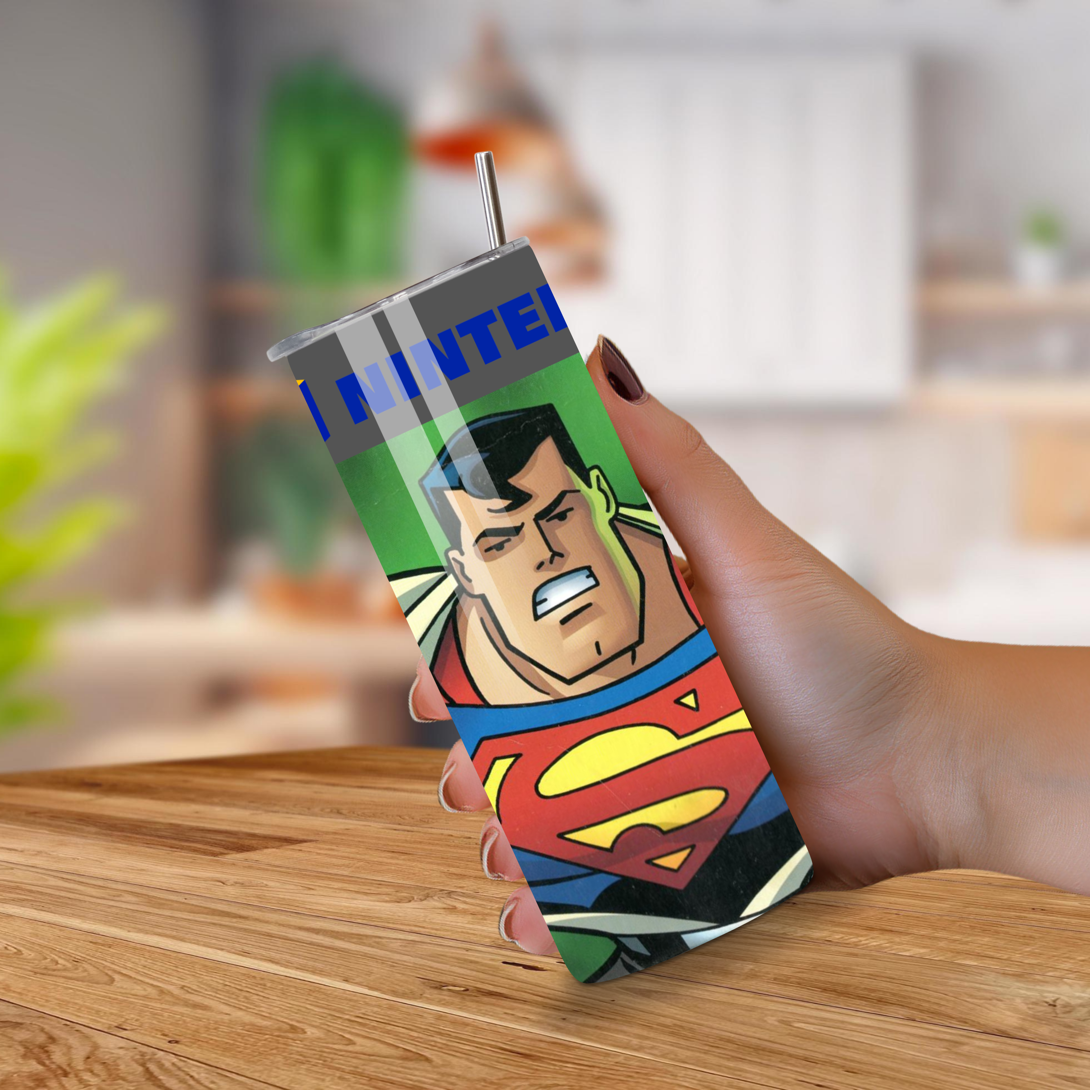 Superman-themed Nintendo tumbler held by a hand on a wooden surface