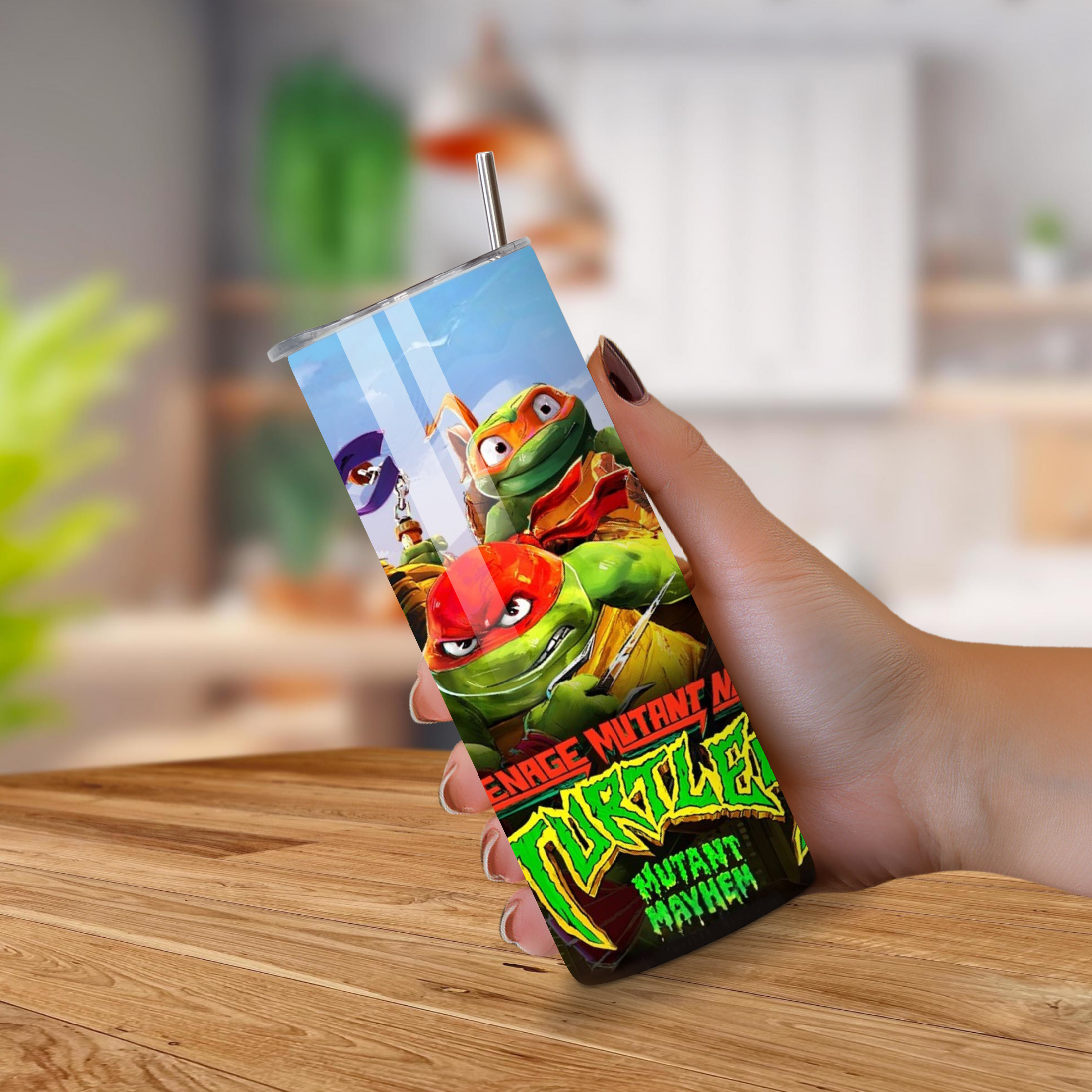 Person holding a Tumbler with a Teenage Mutant Ninja Turtles on a wooden surface.