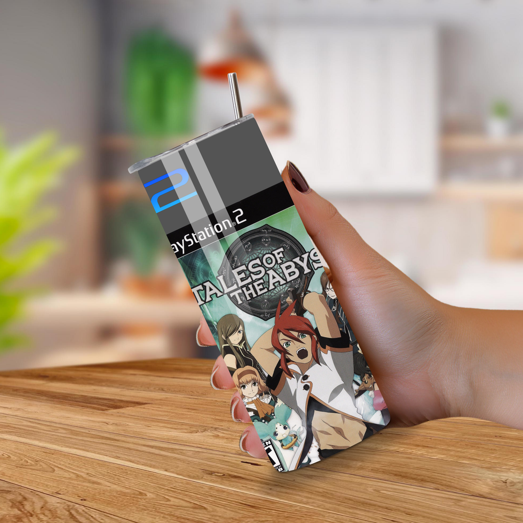 PlayStation 2 tumbler with 'Tales of the Abyss' artwork held by a hand on a wooden surface.
