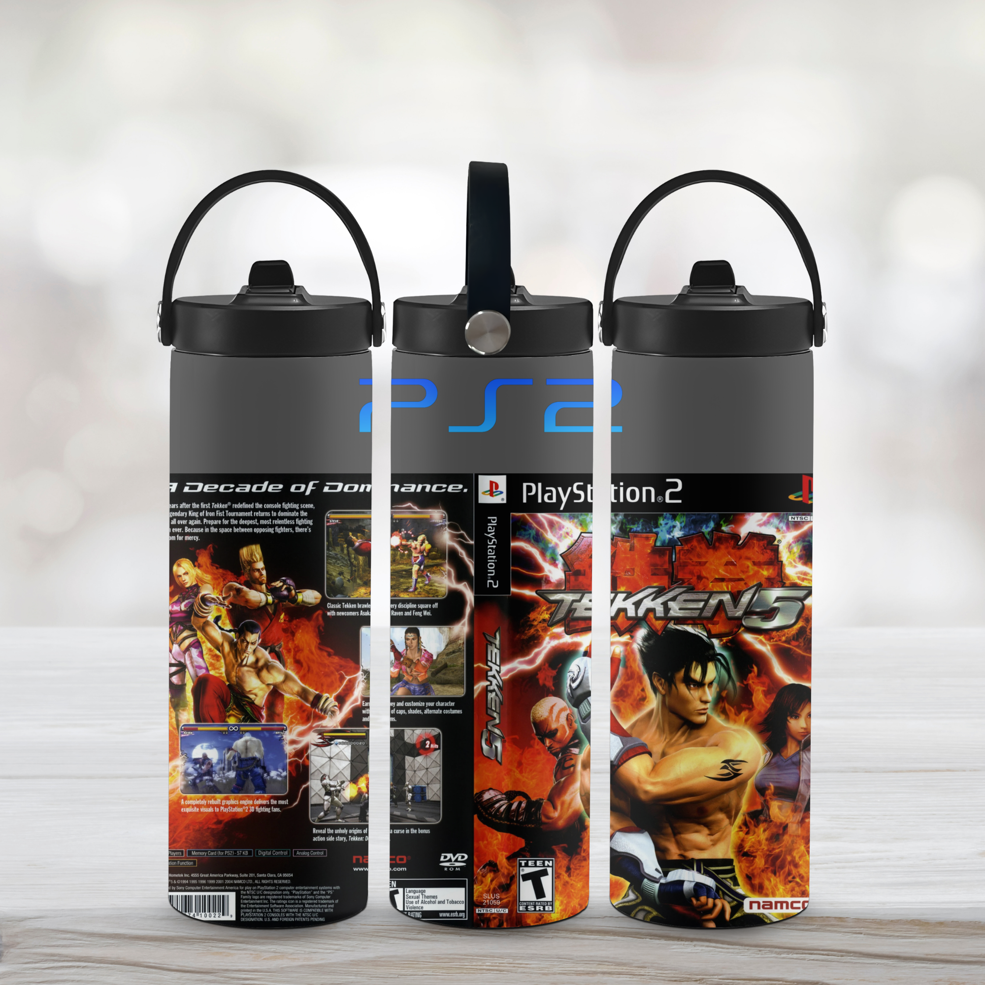Three water bottles with PlayStation 2 and Tekken 5 designs on a light wooden surface.