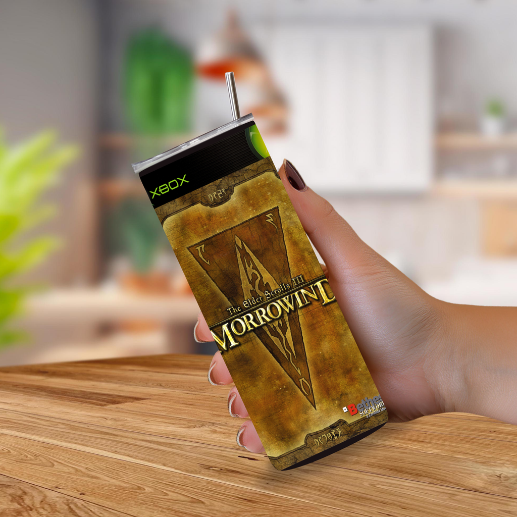 A hand holding a slim, rectangular 20oz Tumbler with a straw, featuring The Elder Scrolls III: Morrowind artwork on the front. The can also shows Xbox branding near the top.