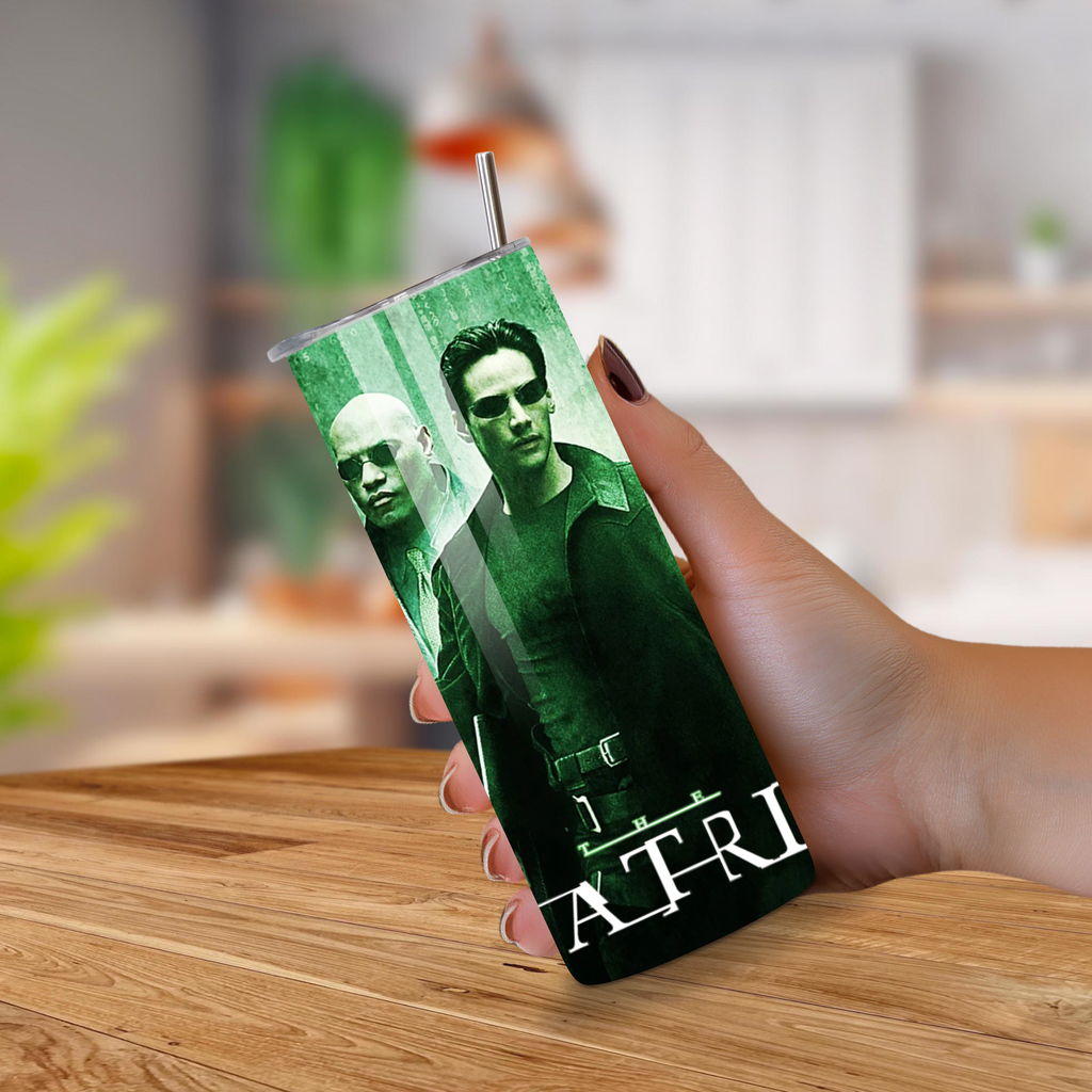 Person holding a tumbler with a green design featuring two characters from the Matrix on a wooden surface.