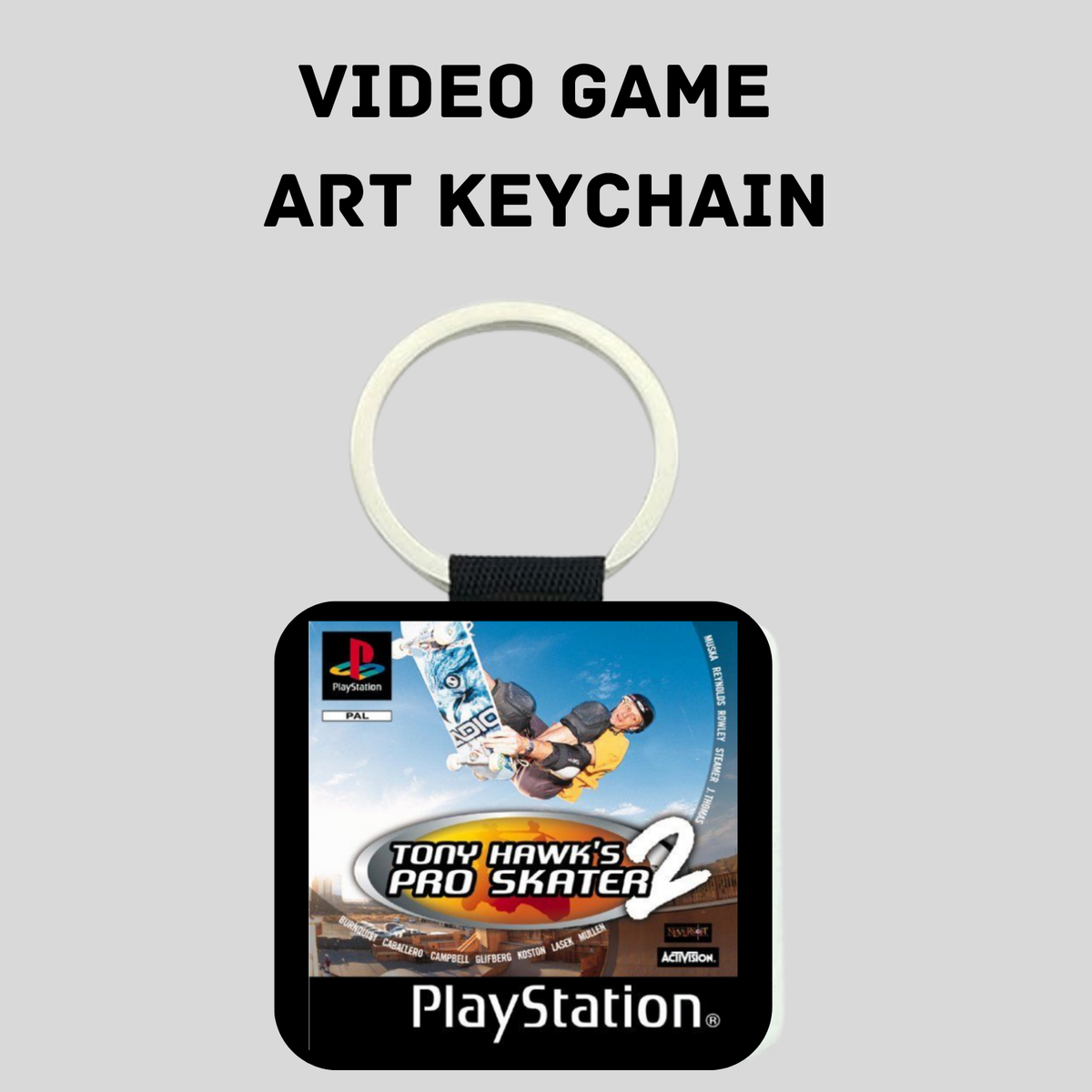 A PlayStation-themed art keychain featuring artwork from the video game Tony Hawk's Pro Skater 2. The keychain has a black rectangular pendant with rounded corners, a printed game cover graphic, and a white plastic key ring on a black strap, shown against a light gray background with the text 'VIDEO GAME ART KEYCHAIN' above it.
