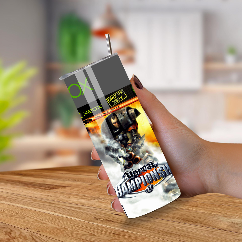 Hand holding a 20oz tumbler of 'Unreal Championship' with a blurred indoor background