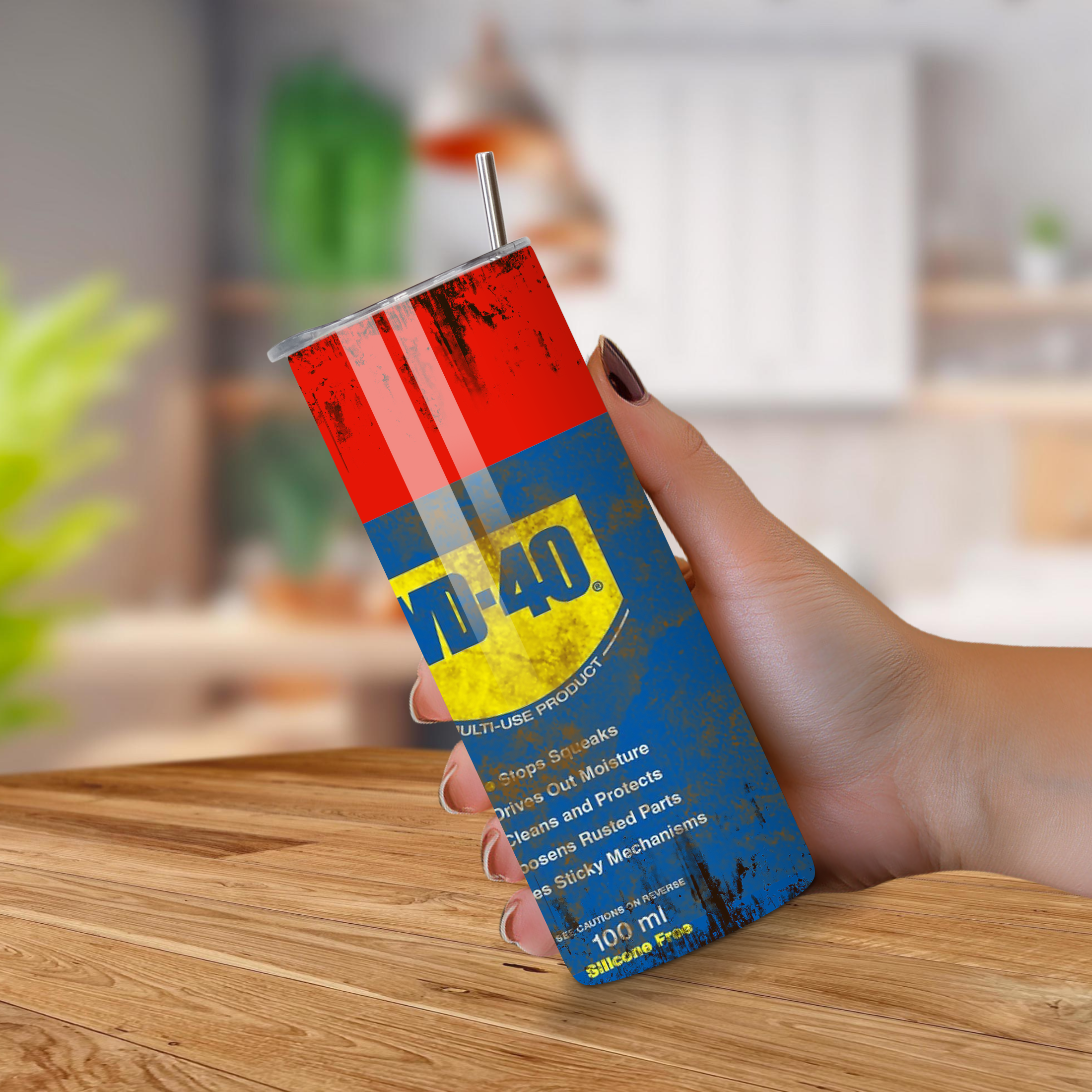 Hand holding a Tumbler with WD-40 image on a wooden surface with a blurred background