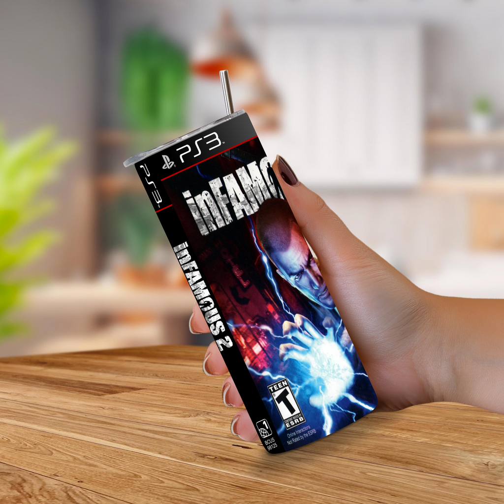 A hand holding a PS3-themed 20oz stainless steel tumbler cover featuring the game Infamous 2 artwork, with a metal straw sticking out, set against a blurred indoor background.