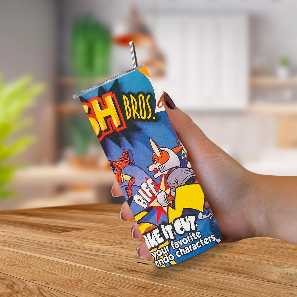 A hand holding a novelty 20oz stainless steel tumbler with a straw, featuring colorful cartoon graphics of Super Smash Bros.